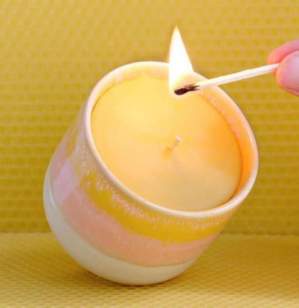 Bienenwachskerze im pinken Keramikbecher wird angezündet