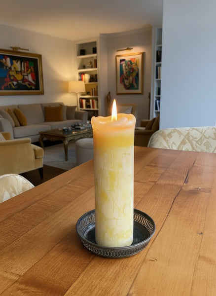 Lit beeswax taper candle in an elegant living room setting